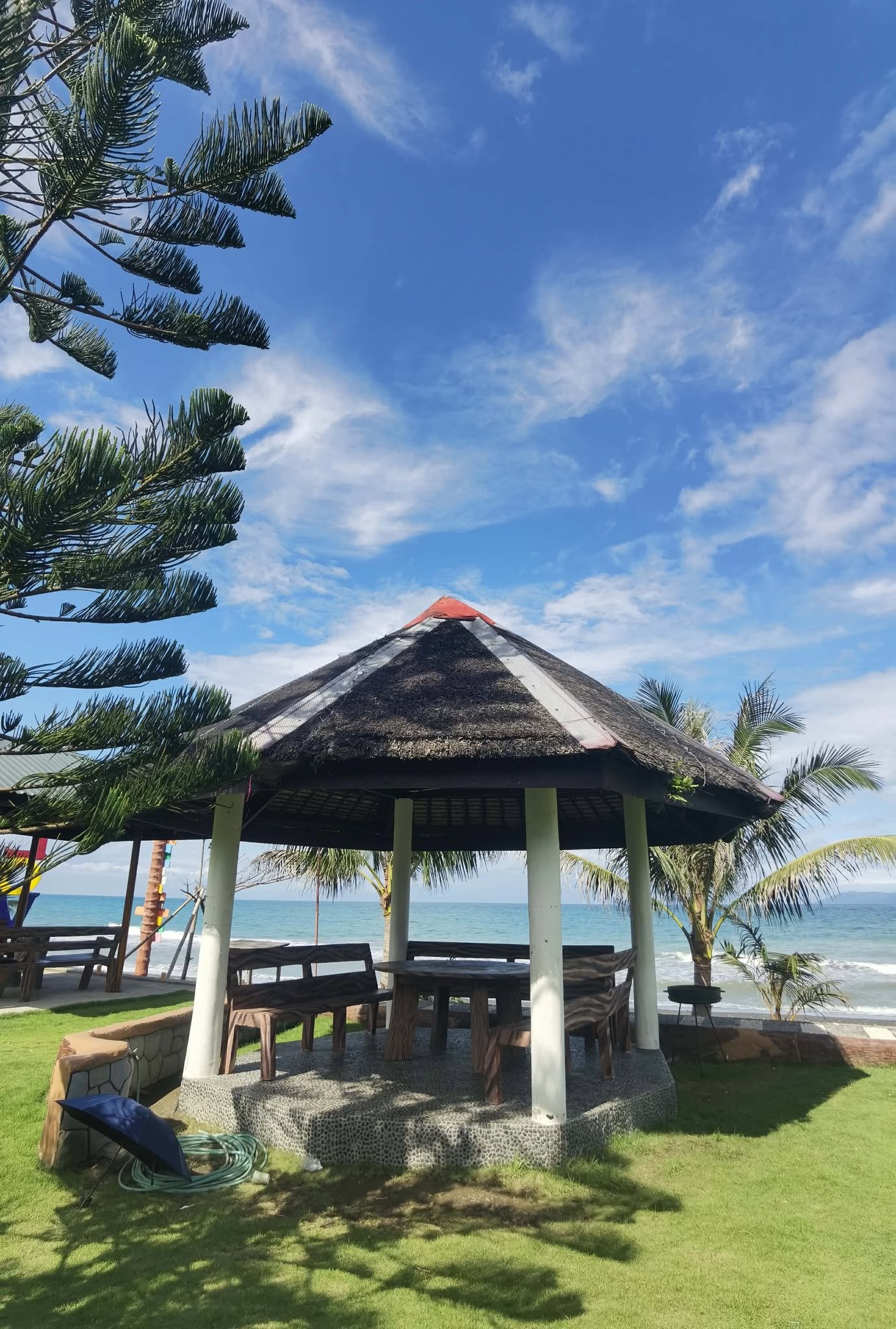 Thatched-roof gazebo on the lawn beside the beach at Balai-Reserve